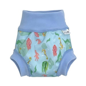 May include: Blue and green swim diaper with a seahorse and seaweed print. The diaper has a blue elastic waistband and a white label with the word "Splash About" on it.