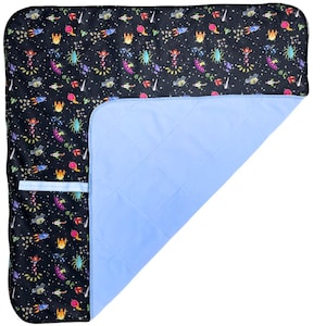 May include: A black and blue quilted play mat with a space-themed print featuring rockets, aliens, and stars. The mat has a pocket on one side.