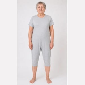 Op de afbeelding: Een lichtgrijze jumpsuit met korte mouwen, een ronde halslijn en verkorte broekspijpen die onder de knie eindigen. Het kledingstuk is gemaakt van een effen, zacht aanvoelende stof met een eenvoudig, gestroomlijnd ontwerp en pasvorm.