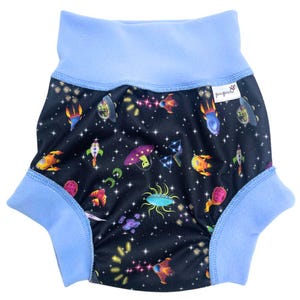 May include: A blue and black reusable cloth diaper with a space-themed print featuring rockets, aliens, and stars. The diaper has a blue fleece lining and the text "pugsy" on the side.