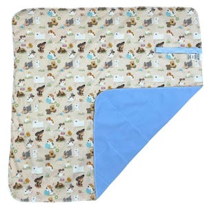 Puede incluir: Una manta impermeable para mascotas de color beige y azul con un patrón repetido de perros en varias poses. La manta tiene una capa impermeable azul en la parte inferior.