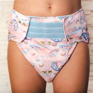 May include: A pink and blue adult diaper with a unicorn and rainbow print. The diaper has a blue adjustable waistband with a white label that says "purity".