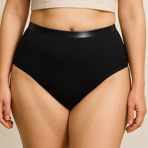 Puede incluir: Bragas negras de cintura alta con una cinturilla ancha. La ropa interior está hecha de una tela lisa y opaca. La cinturilla tiene un ribete negro similar al cuero. La ropa interior está diseñada para brindar cobertura total.