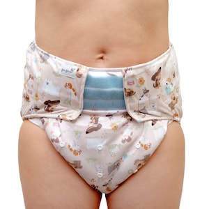 May include: A white adult diaper with a light blue elastic waistband and a print of cartoon dogs and other animals. The diaper has a velcro closure and a label that says "pup-per-fect".
