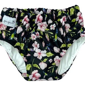 Peut inclure: Sous-vêtements à imprimé floral noir et blanc avec une doublure blanche. L'imprimé présente des fleurs roses, des feuilles vertes et des colibris bleus. Les sous-vêtements ont une étiquette blanche avec le texte "pupujs" dessus.