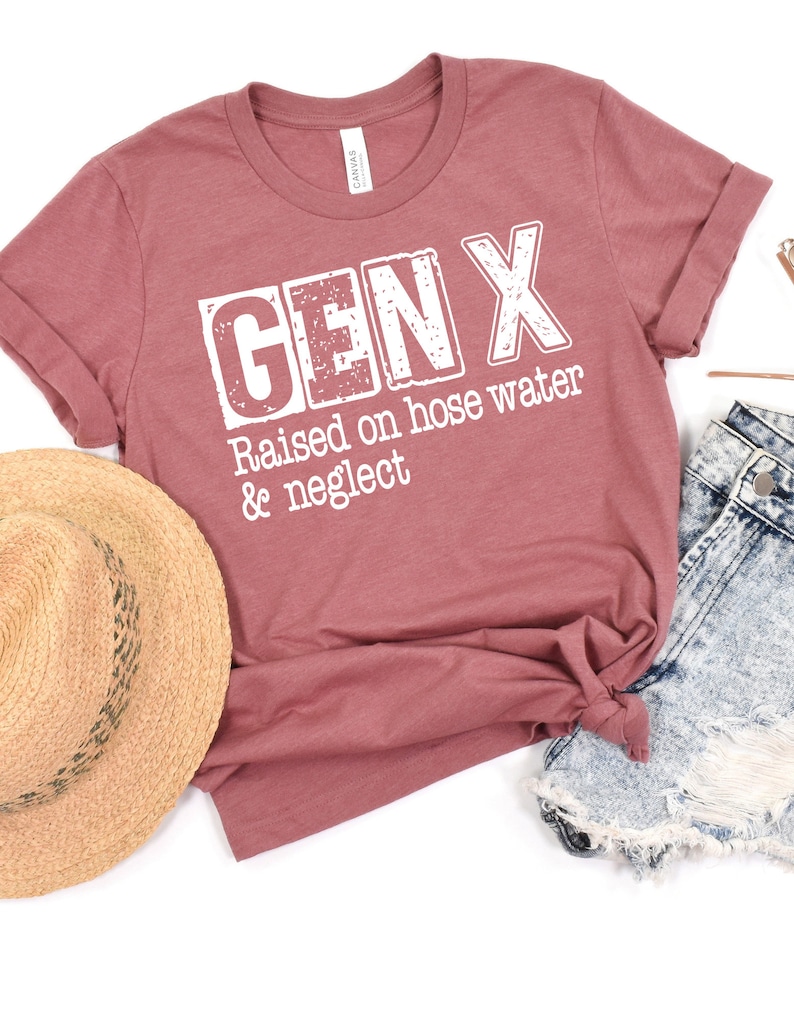 Puede incluir: Una camiseta de color marr&oacute;n rojizo con el texto "GEN X Raised on hose water & neglect" impreso en blanco.