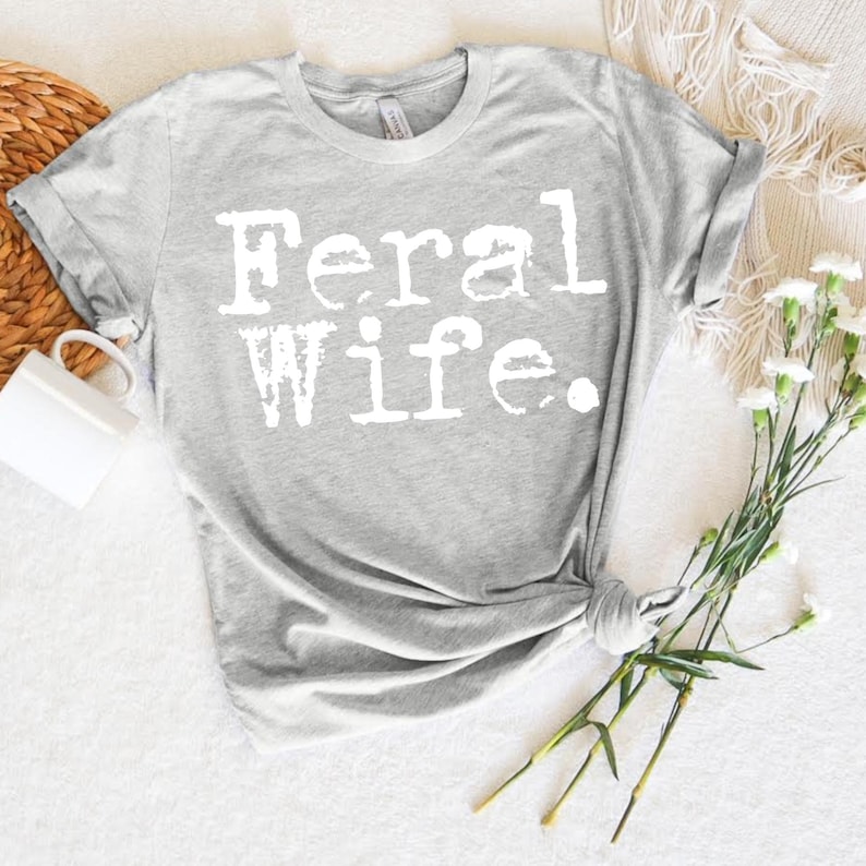 May include: Gray t-shirt with the text "Feral Wife" printed in white.