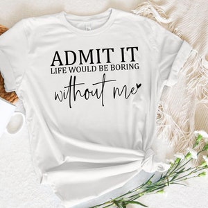 May include: White t-shirt with black text that reads "Admit it, life would be boring without me" with a small heart symbol.