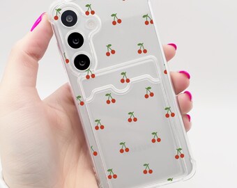 Puede incluir: Carcasa transparente para teléfono con un patrón de cerezas y un soporte para tarjetas incorporado.