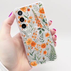 May include: Transparent phone case adorned with a floral pattern of orange flowers and green leaves. The case's clear design allows the phone's colour to be visible. The floral design includes various flower types and foliage.