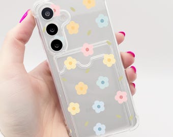 May include: A clear phone case with a floral design. The case has a built-in card holder and features small flowers in pink, yellow, and blue.
