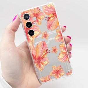 May include: Transparent phone case decorated with a watercolour floral pattern of orange and red hibiscus flowers. The case has a card slot and three camera lenses.