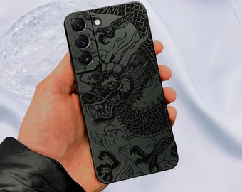 Può includere: Custodia per telefono nera con un design di drago dettagliato. Il drago è nero e bianco e ha un'espressione feroce. La custodia ha un rialzo della fotocamera rialzato con tre obiettivi.