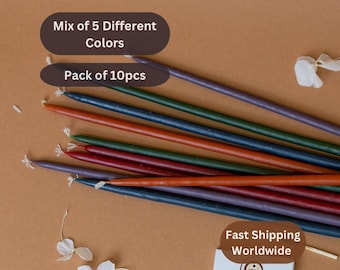 May include: A pack of 10 long, thin birthday candles in a mix of 5 colours: purple, dark blue, green, orange, and red. The candles are arranged in a fan shape on a brown surface. The text "Mix of 5 Different Colours" and "Pack of 10pcs" is visible in the image.