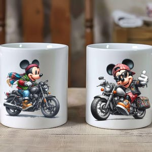 May include: Two white ceramic mugs with a motorcycle and Mickey Mouse design. The mug on the left features Mickey Mouse riding a motorcycle with a blue and green scarf. The mug on the right features Mickey Mouse riding a motorcycle with a red and black bandana.