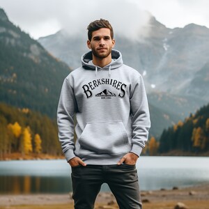 Könnte beinhalten: Ein grauer Kapuzenpullover mit dem Text "Berkshires Massachusetts Est. 1761" und einem Bergketten-Motiv auf der Vorderseite.