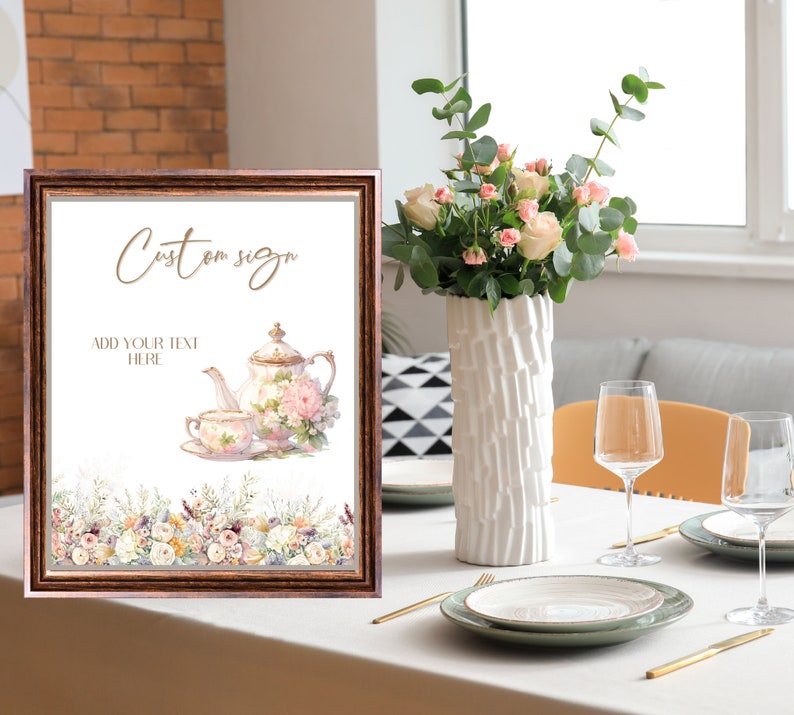 Op de afbeelding: Een printbaar bord met een bruin frame en een witte achtergrond. Het bord heeft een aquarel-illustratie van een theepot en een theekopje met bloemmotieven. De tekst "Custom sign" en "Add your text here" is in goud op het bord gedrukt.