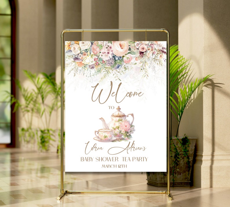 Op de afbeelding: Een welkomstbord voor een baby shower theepartij met een aquarel bloemenontwerp. Het bord toont een theepot en een theekopje met een bloemenpatroon. De tekst luidt "Welkom bij [Name]'s Baby Shower Tea Party op 8 maart".