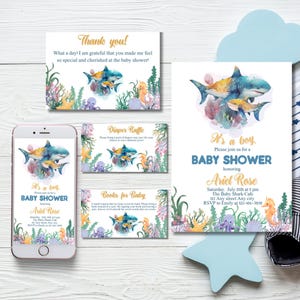 May include: A baby shower invitation set featuring a watercolour shark design. The set includes an invitation, thank you card, diaper raffle card, and a card for books. The invitation reads "It's a boy" with event details.