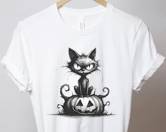 Może przedstawiać: Biały t-shirt z krótkim rękawem z czarno-białą grafiką przedstawiającą kudłatego czarnego kota z dużymi oczami siedzącego na wydrążonej dyni z detalami w kształcie pnączy u podstawy.