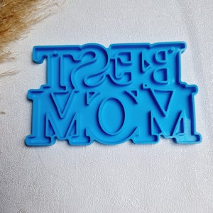 Könnte beinhalten: Blauer Plastik-Ausstecher in Form der Worte "BEST MOM".
