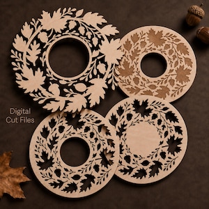 May include: Four circular wooden laser-cut designs featuring intricate patterns of oak leaves and acorns. The light-colored wood pieces have varying levels of detail, with some featuring cut-outs and others engraved. The text Digital Cut Files is visible.