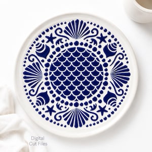 May include: White ceramic plate with a blue seashell and starfish design. The plate features a central pattern of overlapping scales, surrounded by a border of dots and seashell and starfish motifs. The words "Digital Cut Files" are in the lower left corner.