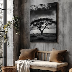 May include: Black and white canvas art print of a lone tree on a plain under a dramatic sky. The artwork hangs above a wooden bench with brown cushions and a cream-colored throw. A woven basket and a wooden stool are also in the room.