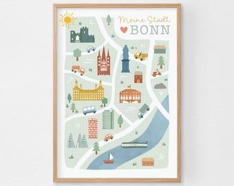 May include: A framed print featuring a map of Bonn, Germany, with illustrations of landmarks, vehicles, and trees. The map is in a light green color scheme with the text "Meine Stadt Bonn" at the top. The frame is made of light brown wood.