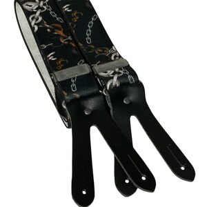 May include: Black braces with a chain link pattern. The braces have black leather ends with metal clips.