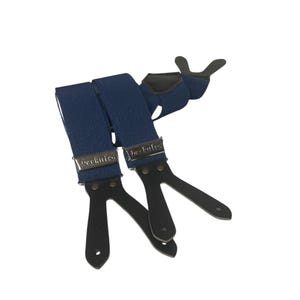 May include: Blue denim suspenders with black leather attachments and silver-colored metal clasps. The suspenders have the word "berkules" printed on the metal clasps. The suspenders are designed to be worn with pants.