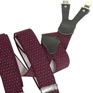 Könnte beinhalten: Bordeauxfarbene Hosenträger mit weißen Punkten und silbernen Clips. Die Hosenträger sind aus gewebtem Stoff und haben eine Leder Rückseite.
