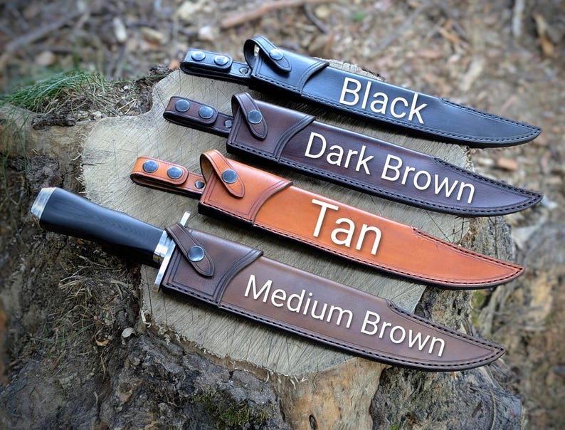 May include: Four leather sheaths in black, dark brown, tan, and medium brown, each with a knife inside. The sheaths are displayed on a tree stump. The colors are labeled with white text: Black, Dark Brown, Tan, and Medium Brown.