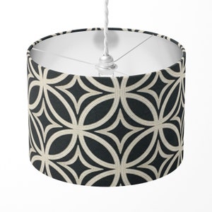 May include: A black and cream patterned drum lampshade with a white cord.