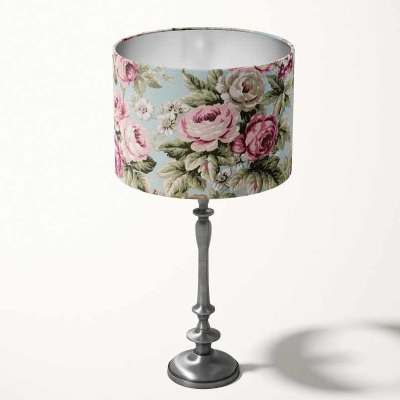Peut inclure: Une lampe de table argent&eacute;e avec un abat-jour &agrave; motifs floraux. L'abat-jour pr&eacute;sente un fond bleu clair avec des roses roses et vertes.