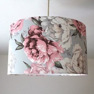 K&ouml;nnte beinhalten: Ein hellblauer Lampenschirm mit einem floralen Muster aus rosa und wei&szlig;en Pfingstrosen.