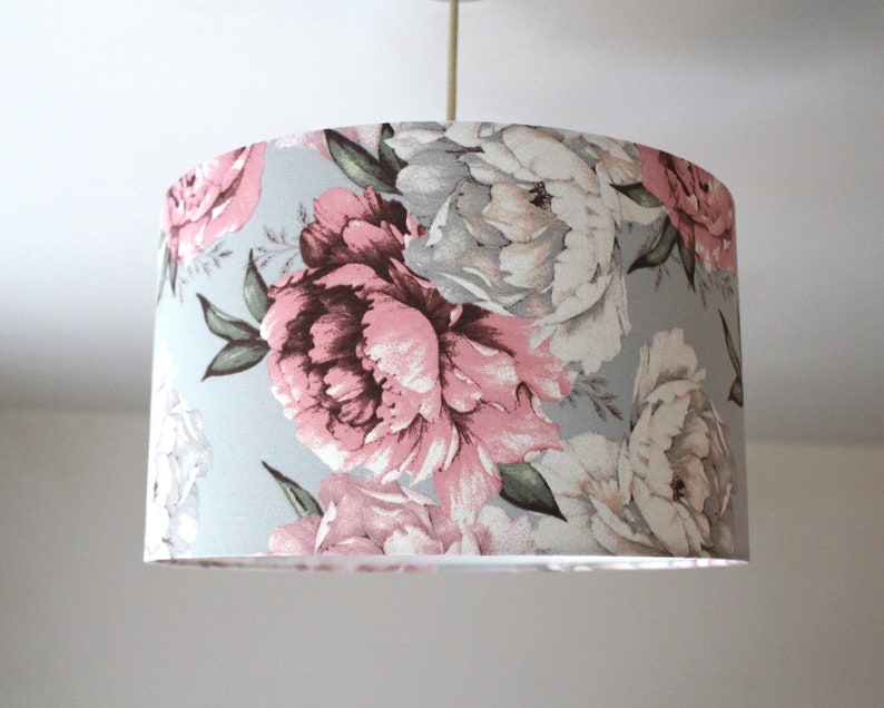 K&ouml;nnte beinhalten: Ein hellblauer Lampenschirm mit einem floralen Muster aus rosa und wei&szlig;en Pfingstrosen.