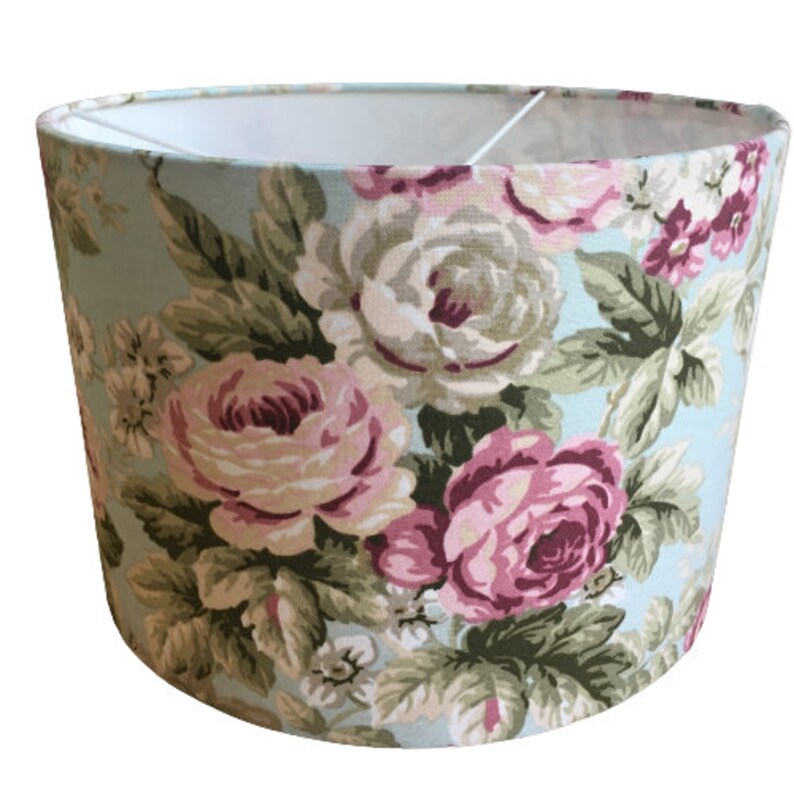 Peut inclure: Un abat-jour bleu clair avec un motif floral compos&eacute; de roses roses et blanches et de feuilles vertes.
