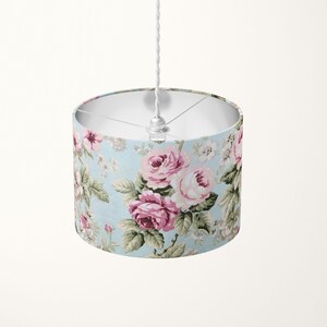 Peut inclure: Un luminaire de plafond blanc avec un abat-jour &agrave; motif floral bleu clair orn&eacute; de roses roses.