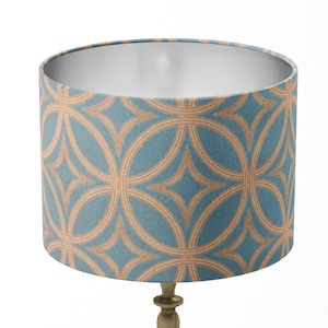 May include: A blue and gold lampshade with a geometric pattern. The lampshade is cylindrical and has a white interior.