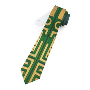May include: A green and gold patterned tie with a geometric design. The tie has a narrow width and a pointed tip.