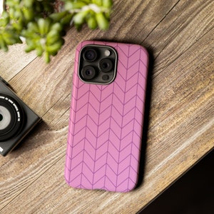 May include: A pink phone case with a chevron pattern. The case has a raised camera bump with three lenses.