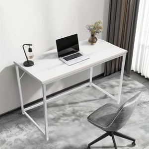 May include: White desk with a laptop, lamp, and vase of flowers on top. The desk has a white metal frame and a white tabletop. A grey office chair is in the foreground.