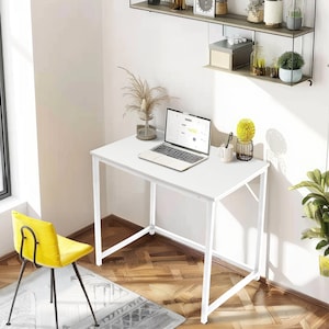 May include: White computer desk with a laptop, a potted plant, and a pencil holder on the surface. The desk has a white metal frame and is sitting on a wooden floor.