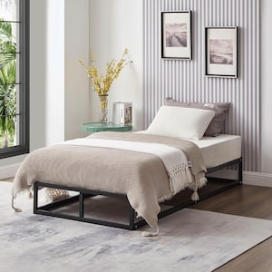 May include: A black metal platform bed frame with a beige blanket and white pillow. The bed frame has a slatted base and is sitting on a light grey rug.