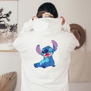 May include: White hooded sweatshirt with a blue Stitch character from Lilo & Stitch printed on the back.