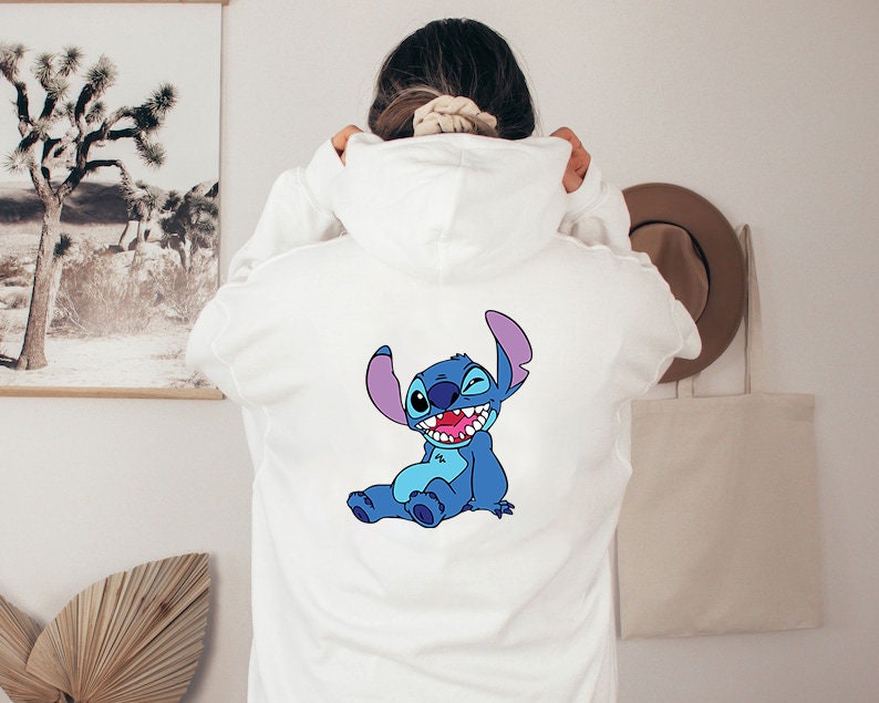 May include: White hooded sweatshirt with a blue Stitch character from Lilo & Stitch printed on the back.