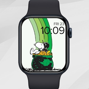 May include: A black smartwatch displays a cartoon image of Snoopy sitting on a pot of gold at the end of a rainbow. The time is 10:09, and the date is Friday, the 23rd.