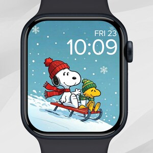 May include: A smartwatch displays a winter scene with Snoopy and Woodstock sledding. Snoopy wears a red hat and scarf, while Woodstock sports a green hat. The screen shows the date, Friday the 23rd, and the time, 10:09, with snowflakes.