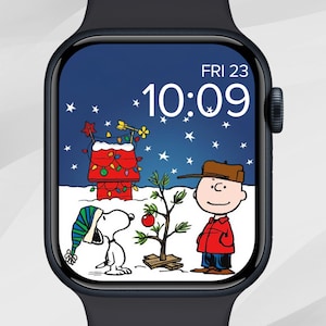 Può includere: Un display di smartwatch nero mostra una scena natalizia con Snoopy, Charlie Brown e la cuccia di Snoopy decorata con luci. L'ora è 10:09 di venerdì 23 dicembre. Lo sfondo è una notte nevosa con stelle.